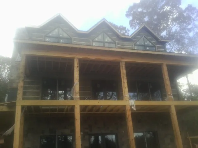 Dormers and porch framing on a large log home under construction — Roof Coating work by our crew in Alexandria